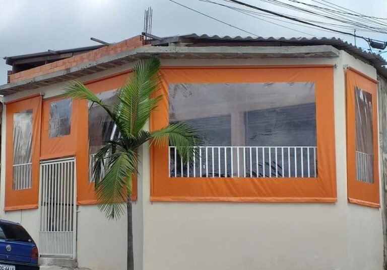 Cortinas de lona laranja com visor transparente fechando a varanda de uma casa