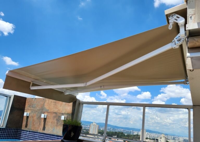 Toldo retrátil articulado aberto sobre terraço com vista para a cidade
