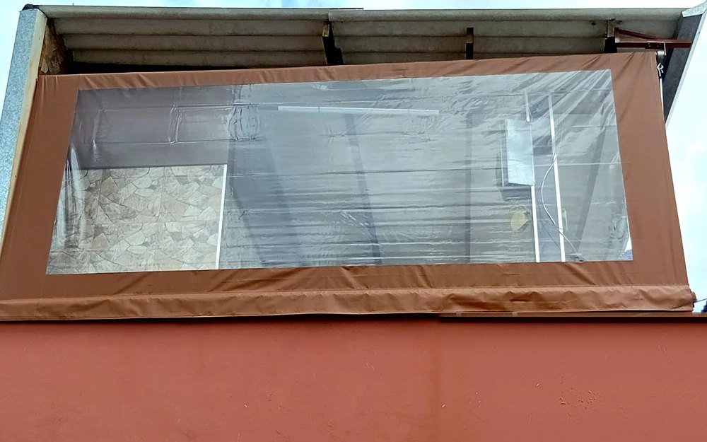 Cortina de lona marrom com visor transparente fechando varanda