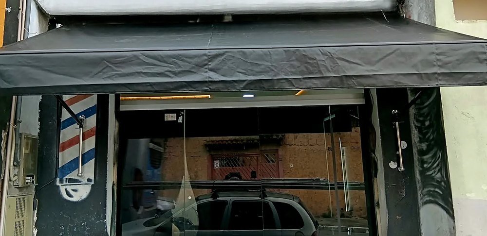 Toldo de lona preta sobre a fachada de uma barbearia